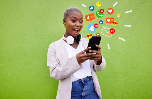 Surprise, black woman and reading phone emojis, social media icons and wow facial expression for networking notification. App opinion, cellphone communication or shocked user on green background wall.