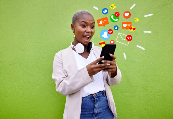 Surprise, black woman and reading phone emojis, social media icons and wow facial expression for networking notification. App opinion, cellphone communication or shocked user on green background wall.